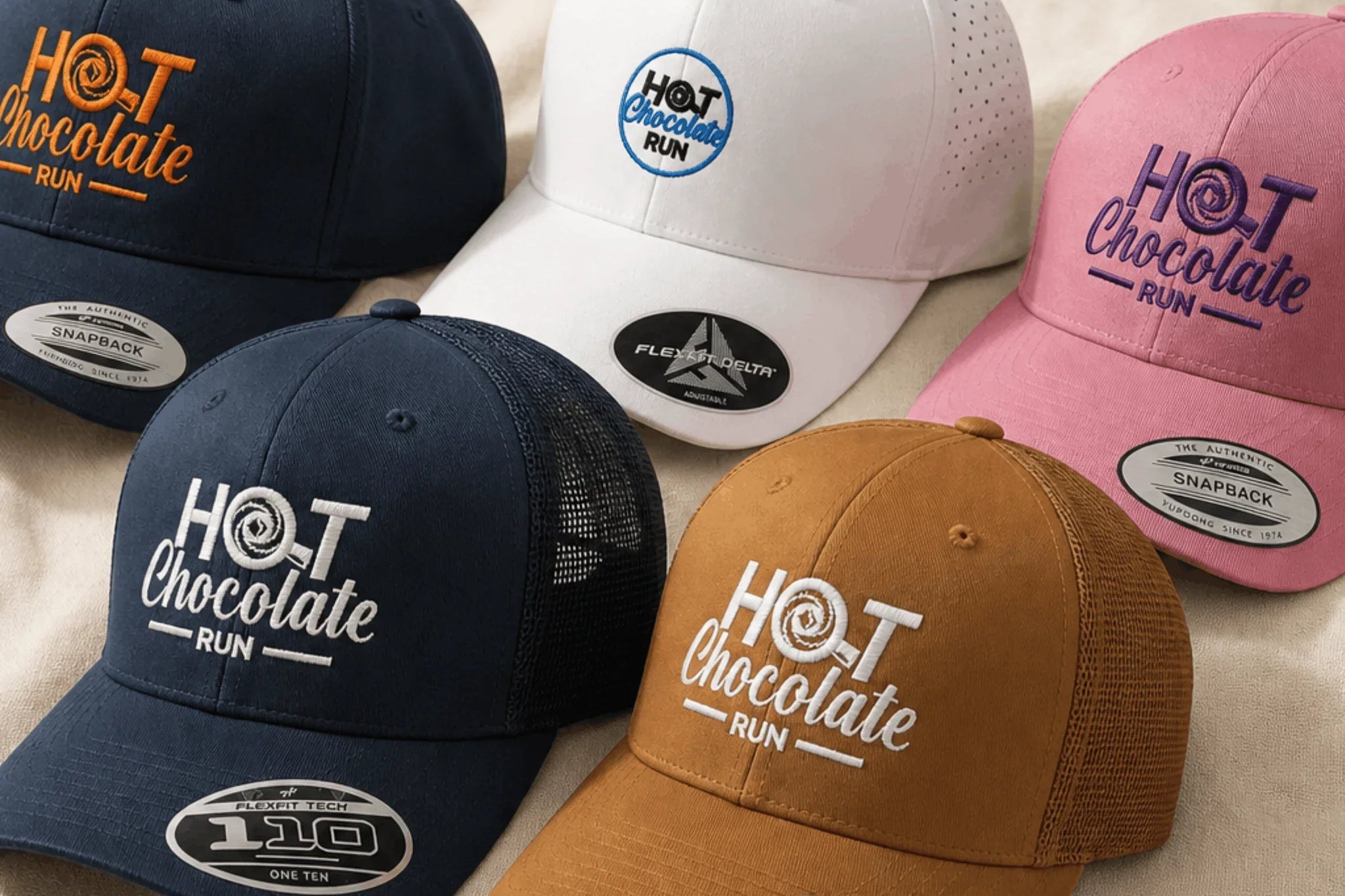 Five baseball caps with 'Hot Chocolate Run' branding on a beige surface