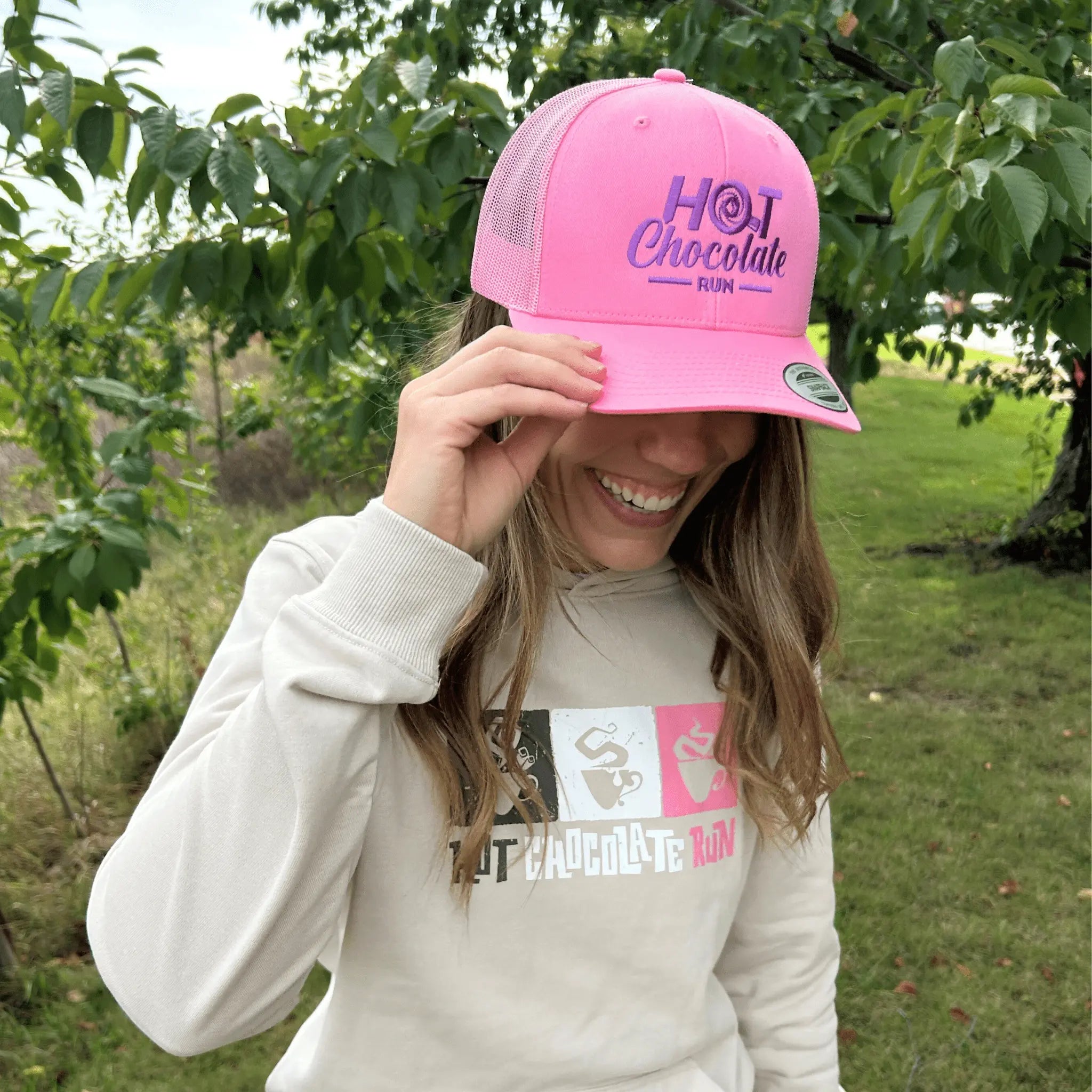 Woman posing outside in pink trucker hat with Hot Chocolate Run logo
