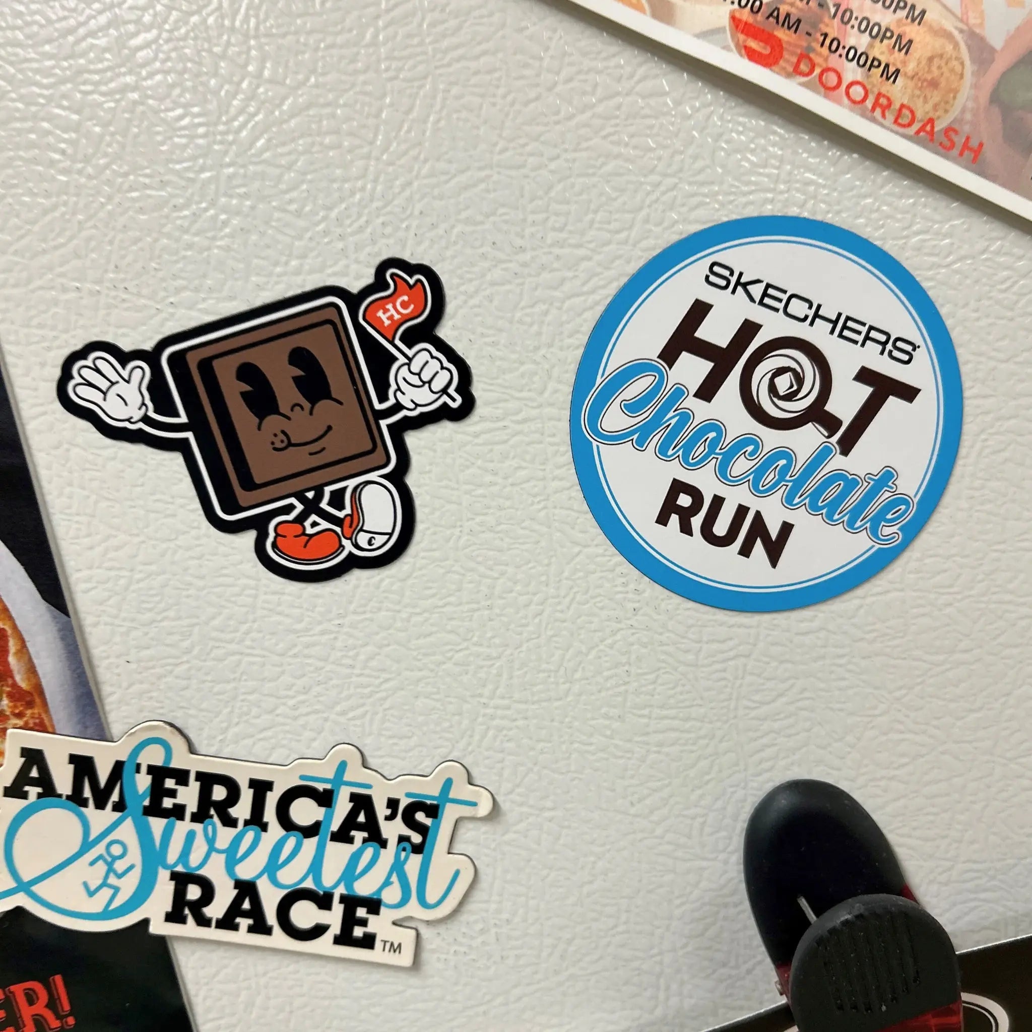 Magnets on a refrigerator surface with 'Skechers Hot Chocolate Run' and a Chocolate Square Character