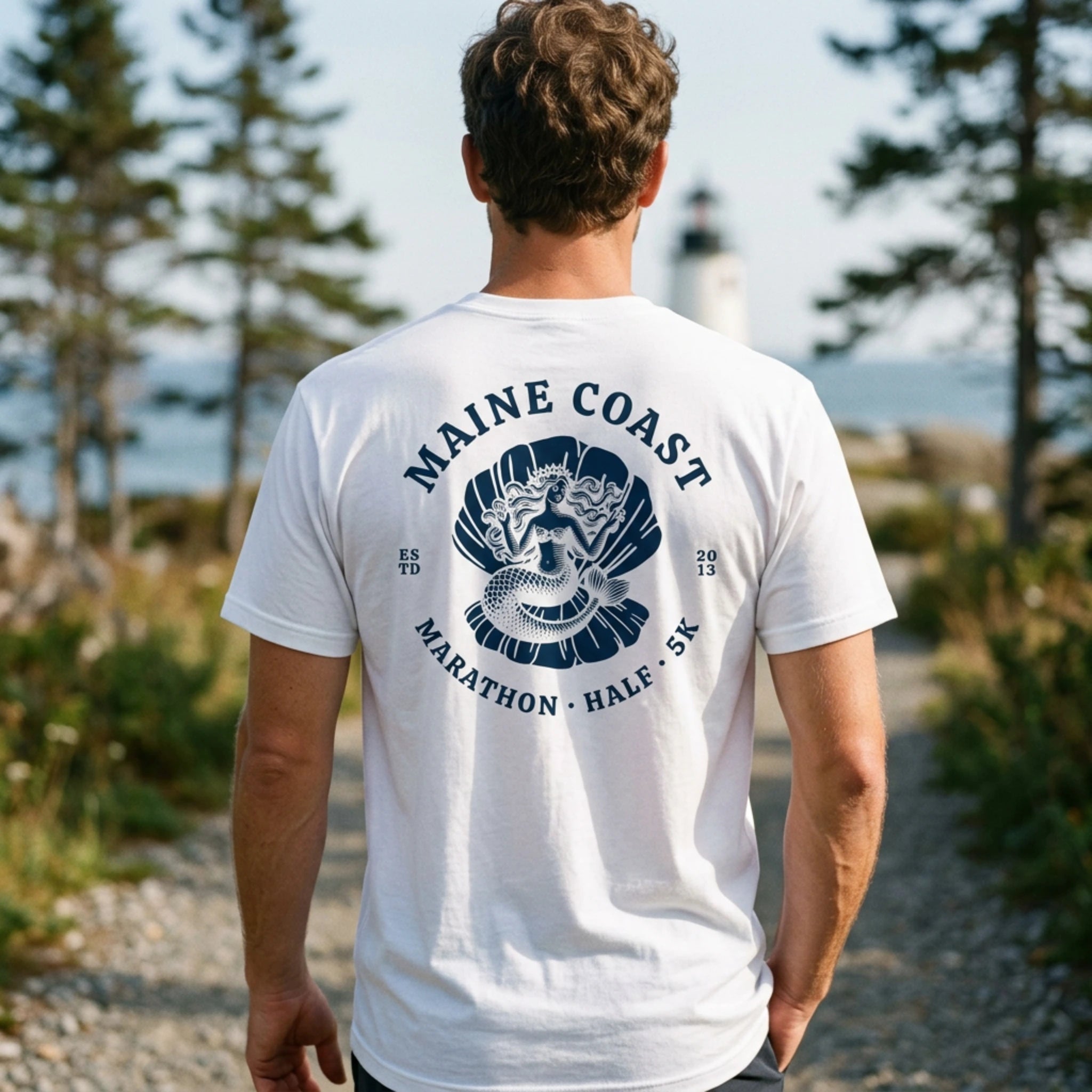 Person wearing a white t-shirt with 'Maine Coast Marathon' design outdoors.