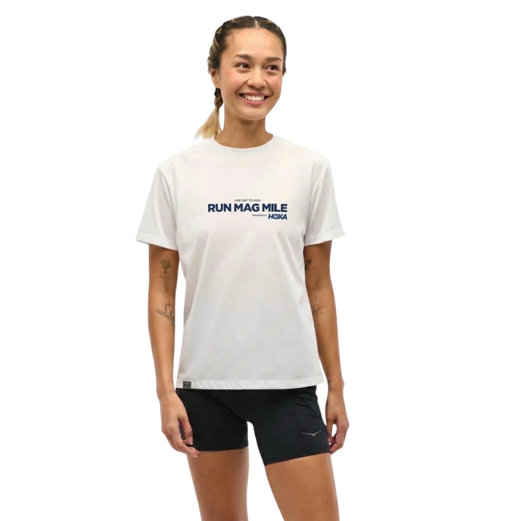 Woman wearing white tee with chest text saying Run Mag Mile One Day to Run presented by HOKA