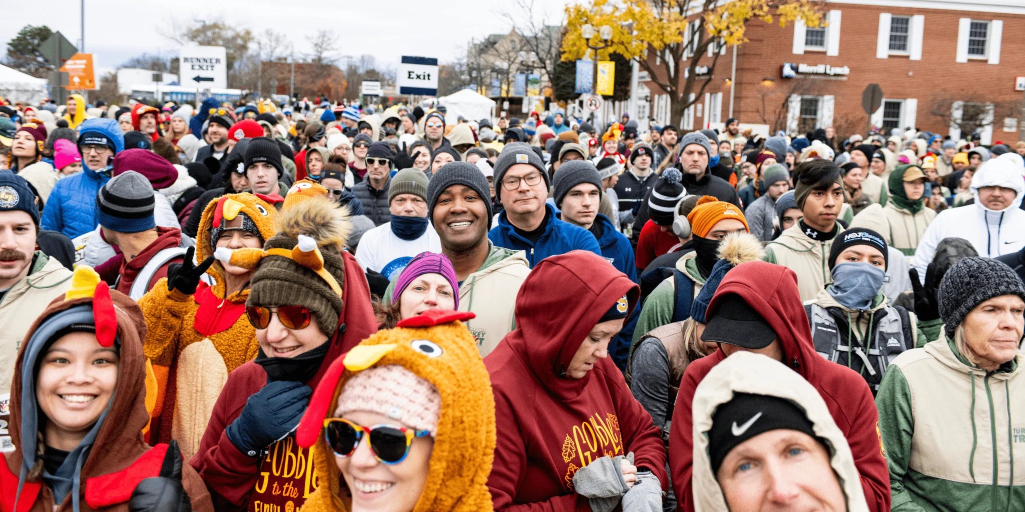 Large crowd of people wearing winter clothing and Turkey Trot apparel at the start line