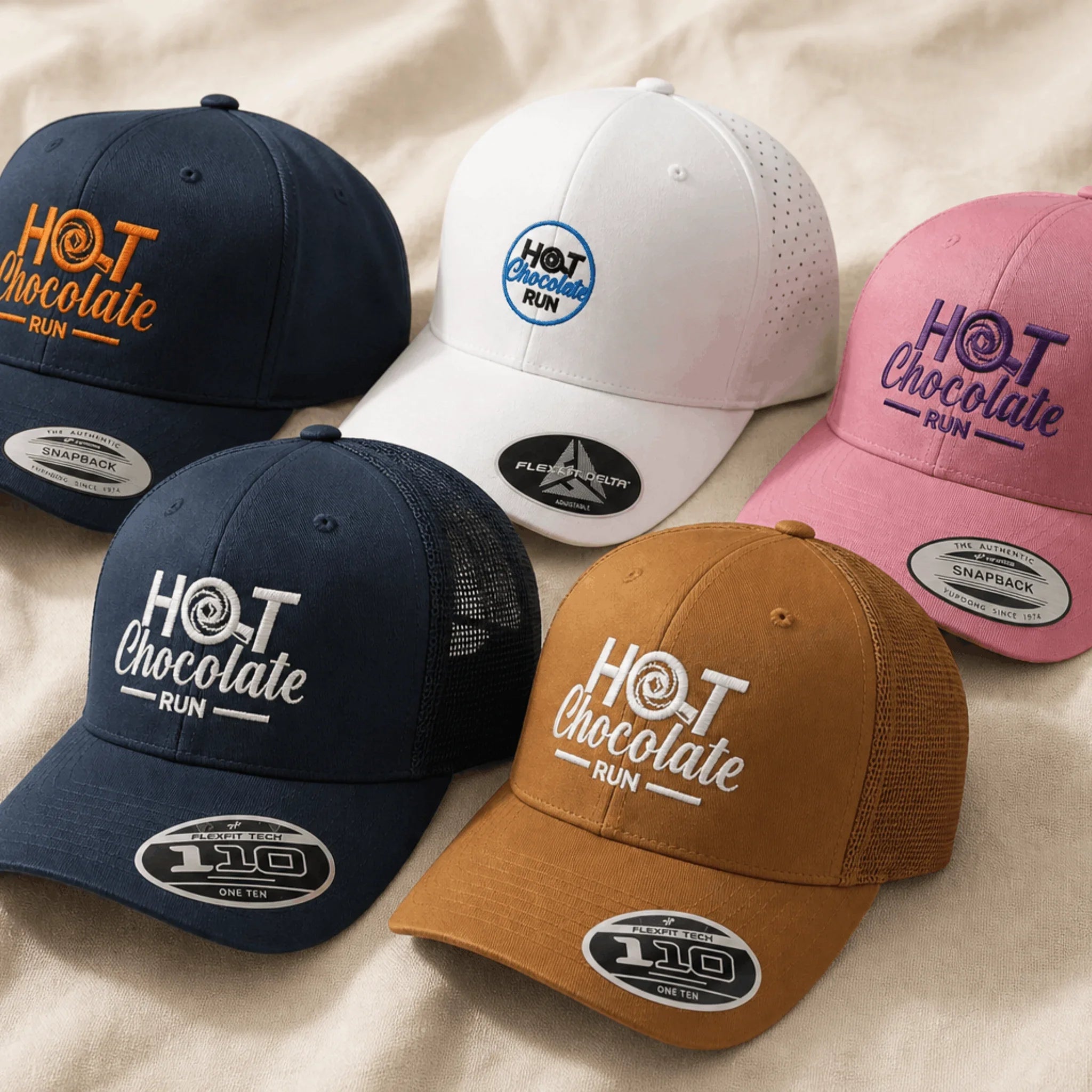 Five baseball caps with 'Hot Chocolate Run' branding on a beige surface