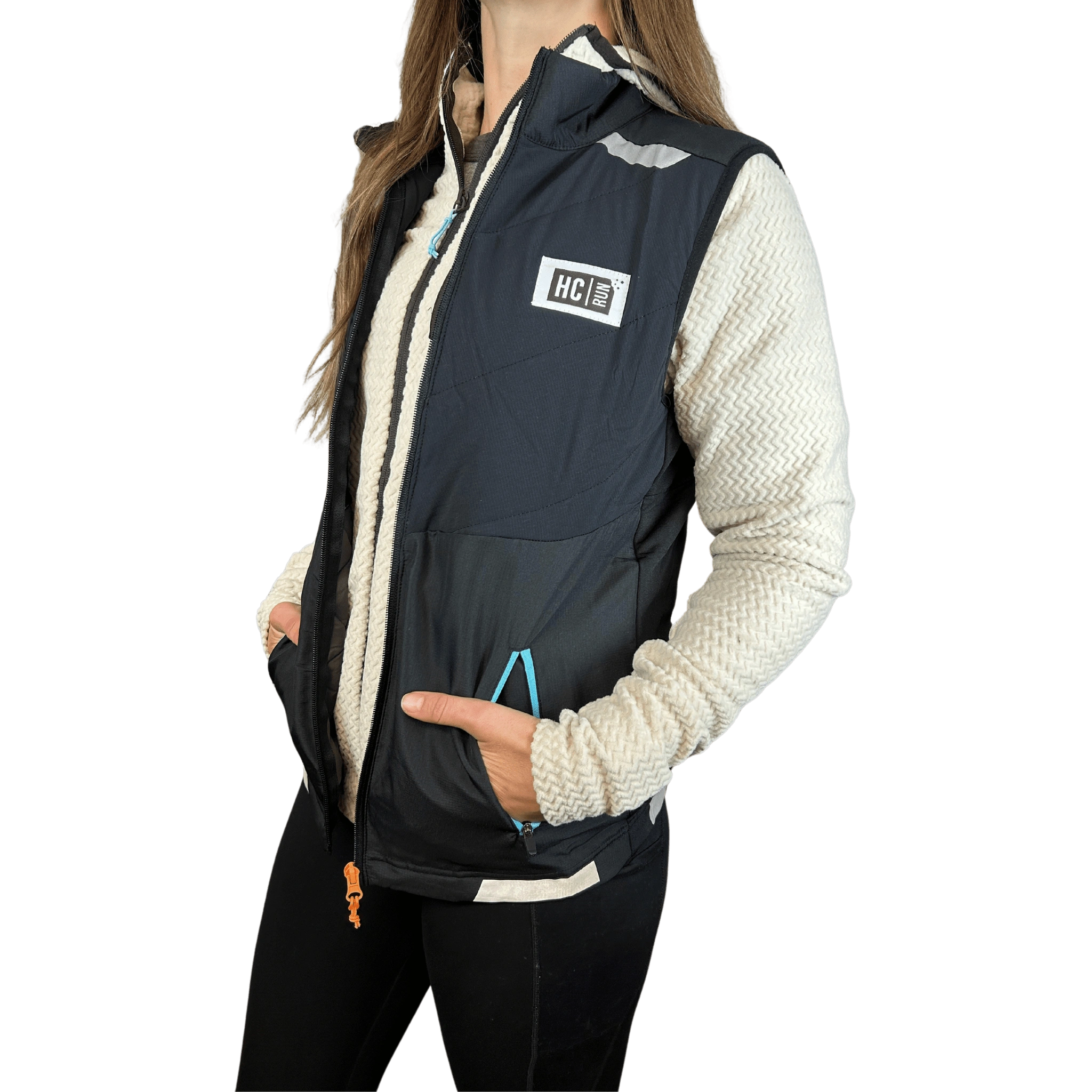 Person wearing a white fleece jacket under a black running vest with HC Run logo on left chest and hands in pocket
