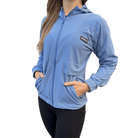 Person wearing a light blue jacket with hands in pocket and Hot Chocolate Run logo on left chest