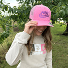 Woman posing outside in pink trucker hat with Hot Chocolate Run logo 