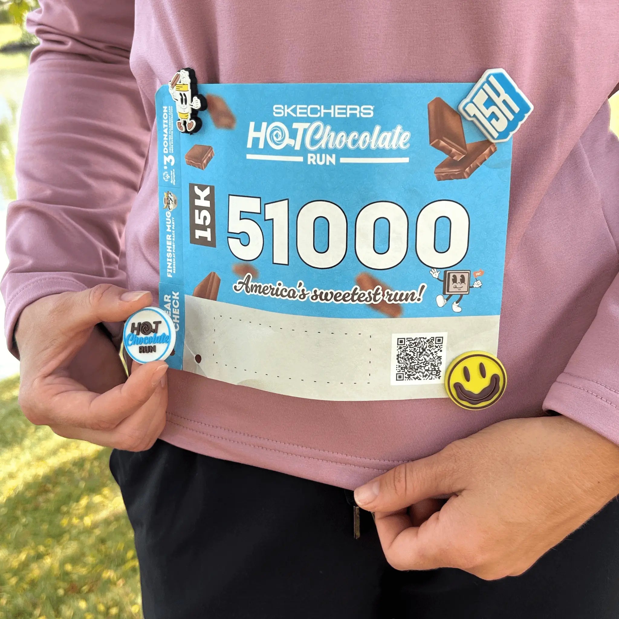 Person holding a Skechers Hot Chocolate Run race bib and putting on a meSnap