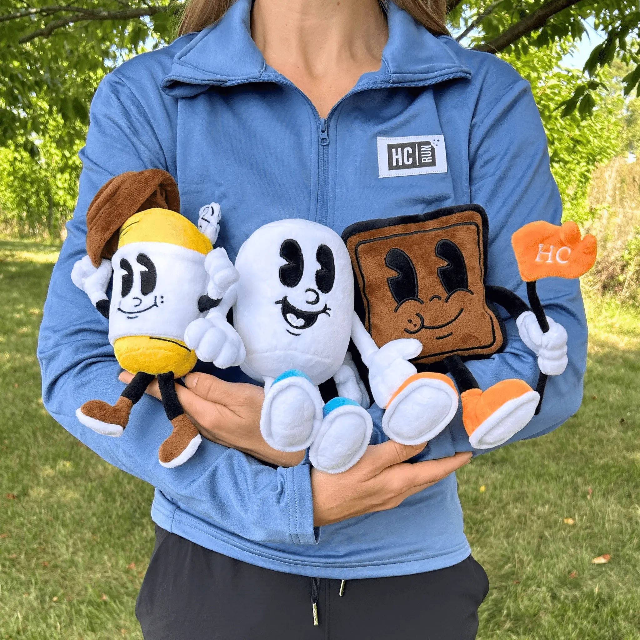 Person cradling three Hot Chocolate Run character plushies in their hands