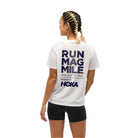 Woman wearing white tee with back design reads Run Mag Mile One Day to Run presented by HOKA