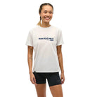 Woman wearing white tee with chest text saying Run Mag Mile One Day to Run presented by HOKA