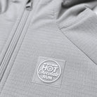 Close-up of a light gray zippered jacket with a circular Skechers Hot Chocolate Run rubber stamp