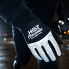 A close-up of a person wearing a black and white reflective running glove with the text 'HOT Chocolate RUN' printed on the back of the hand