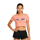 Woman wearing a peach-colored 'Old Port' crop tee and black shorts